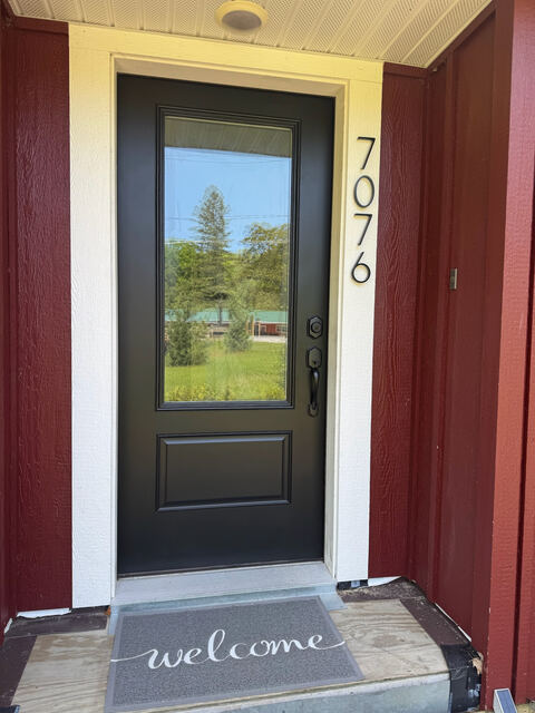 Front entry door with house number and welcome mat