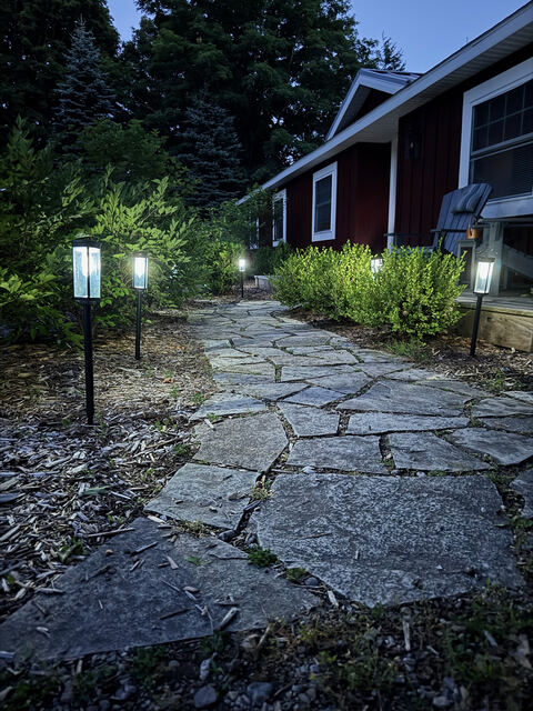 Lantern-lit stone path leading to the cabin at dusk